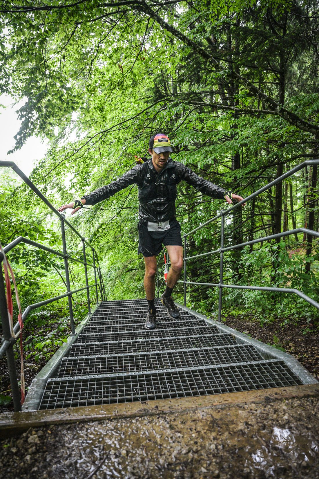 Jack Chamberlain jumping down a flight of steps in the rain at the Mozart 100 by UTMB.